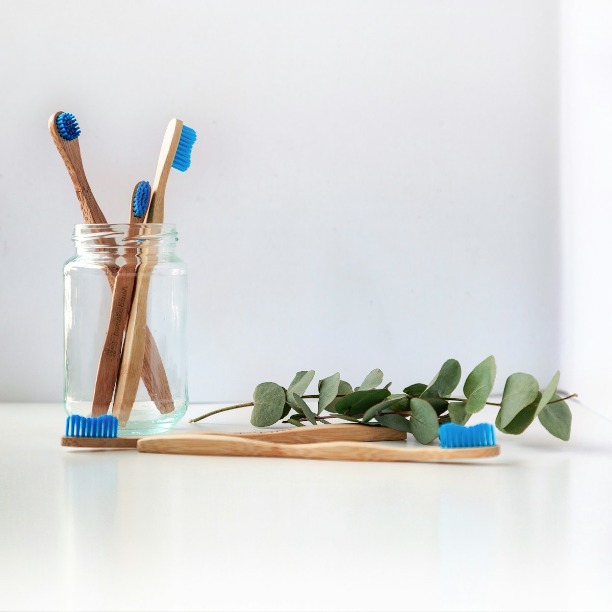 Bamboo toothbrushes beside a eucalyptus sprig, representing natural oral care routines such as oil pulling discussed by Orchid Dental Wellness, Bhopal